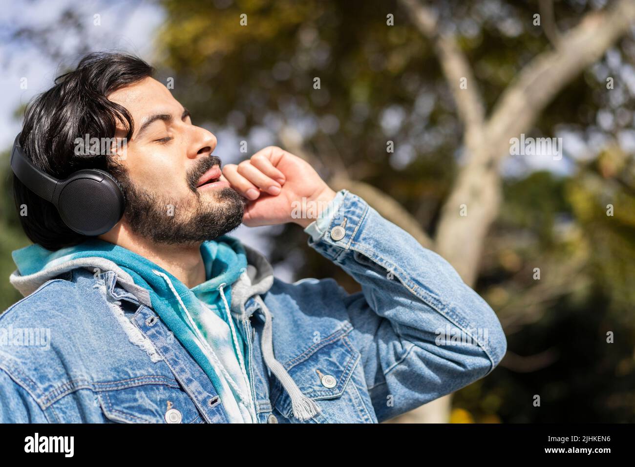 Young latin man listening to music outdoors with headphones. Expression of happiness, winning attitude. Stock Photo