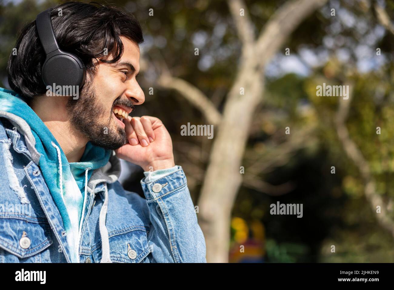 Young latin man listening to music outdoors with headphones. Expression of happiness, winning attitude. Stock Photo