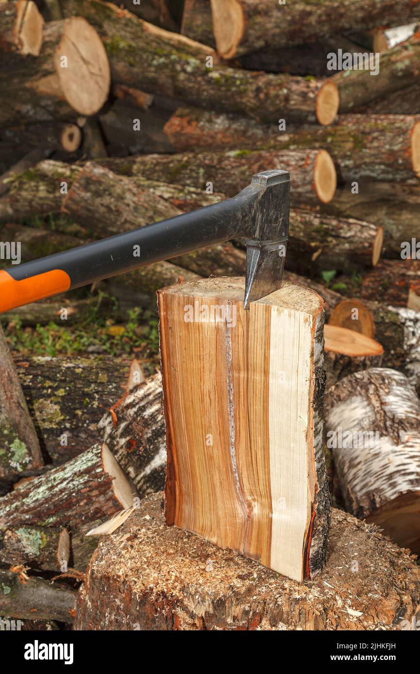 A special axe for splitting wood is stuck into the log. The axe splits