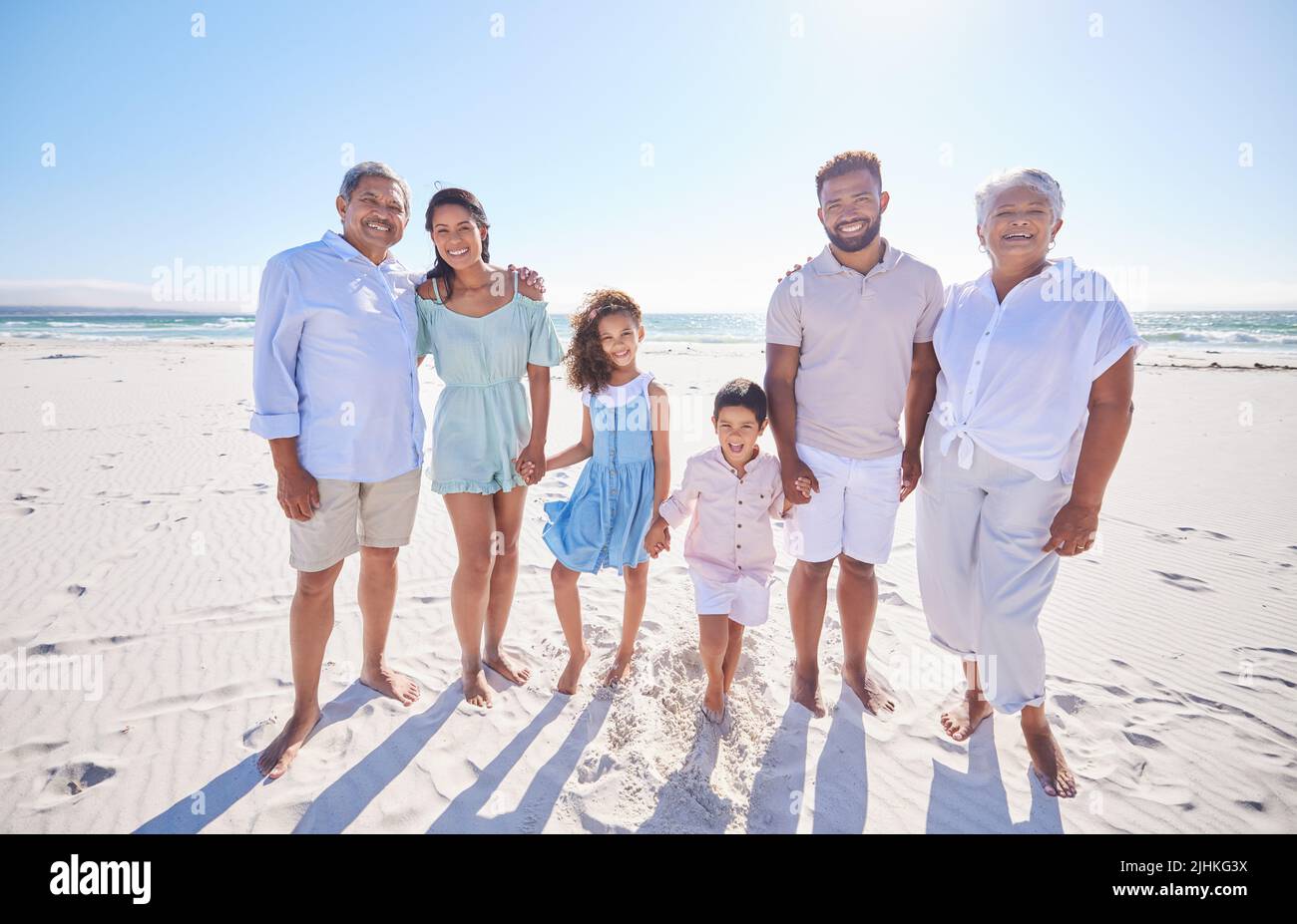 Multi generation family standing together at the beach. Mixed race