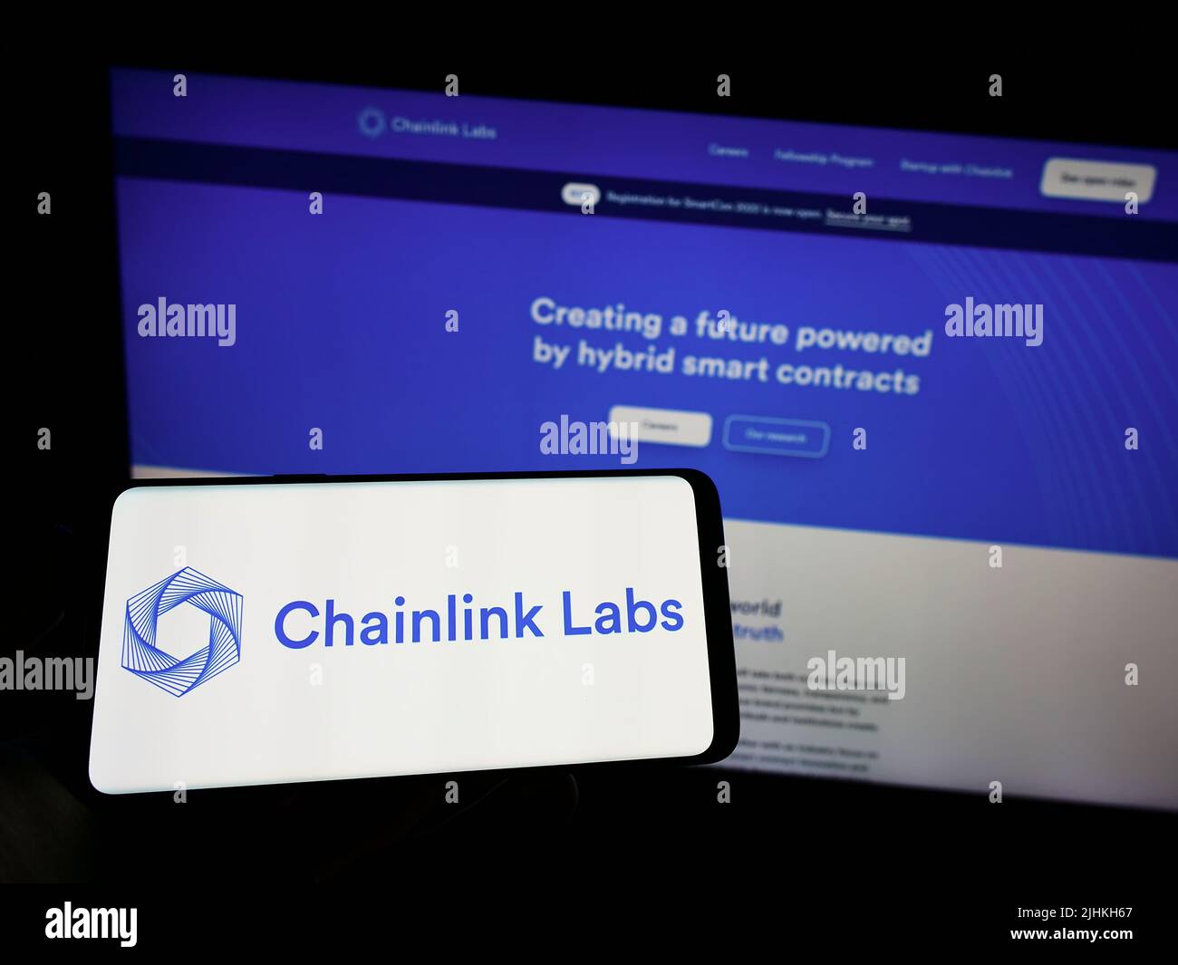 Person holding mobile phone with logo of American blockchain company Chainlink Labs on screen in front of web page. Focus on phone display. Stock Photo
