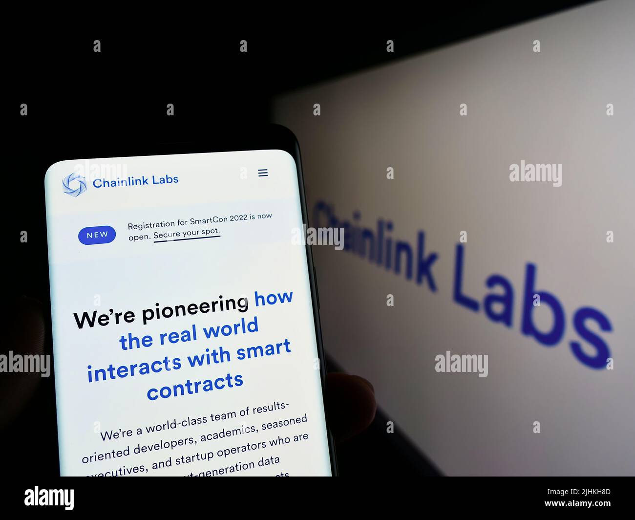 Person holding smartphone with webpage of US blockchain company Chainlink Labs on screen in front of logo. Focus on center of phone display. Stock Photo
