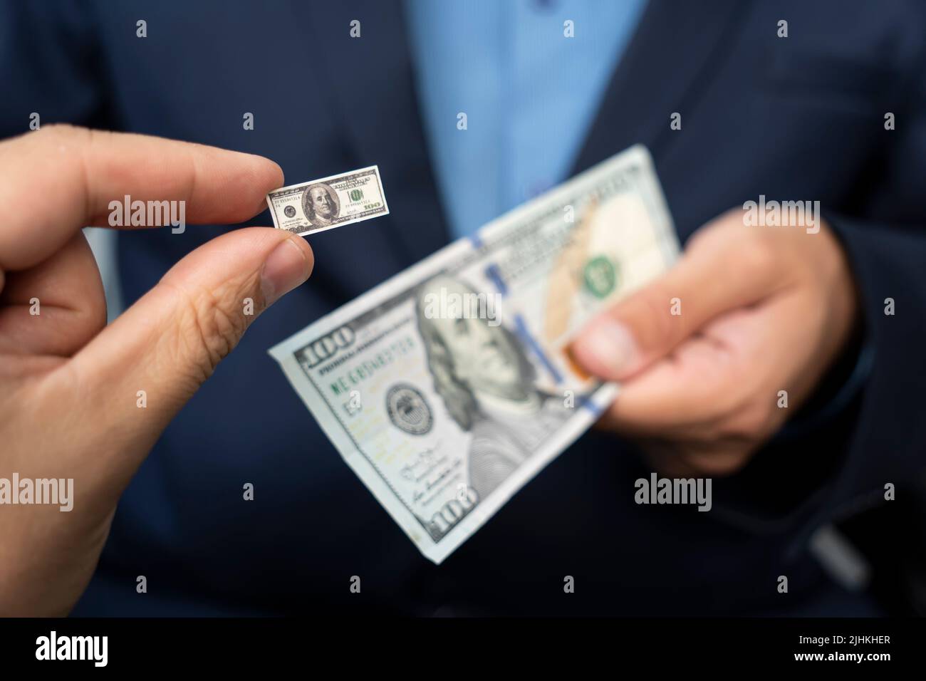 the concept of inflation and falling incomes. a small hundred-dollar bill in the businessman's hand Stock Photo
