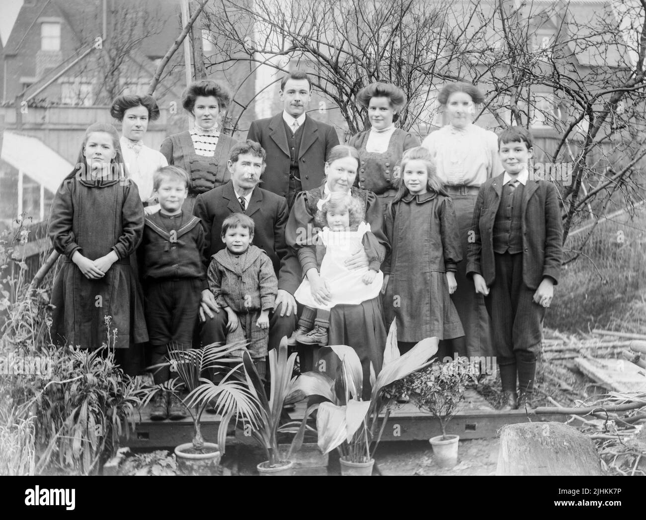An early 20th Century Edwardian black and white photograph showing g a British Family. Men, women and children, posing for the camera in a garden. Stock Photo