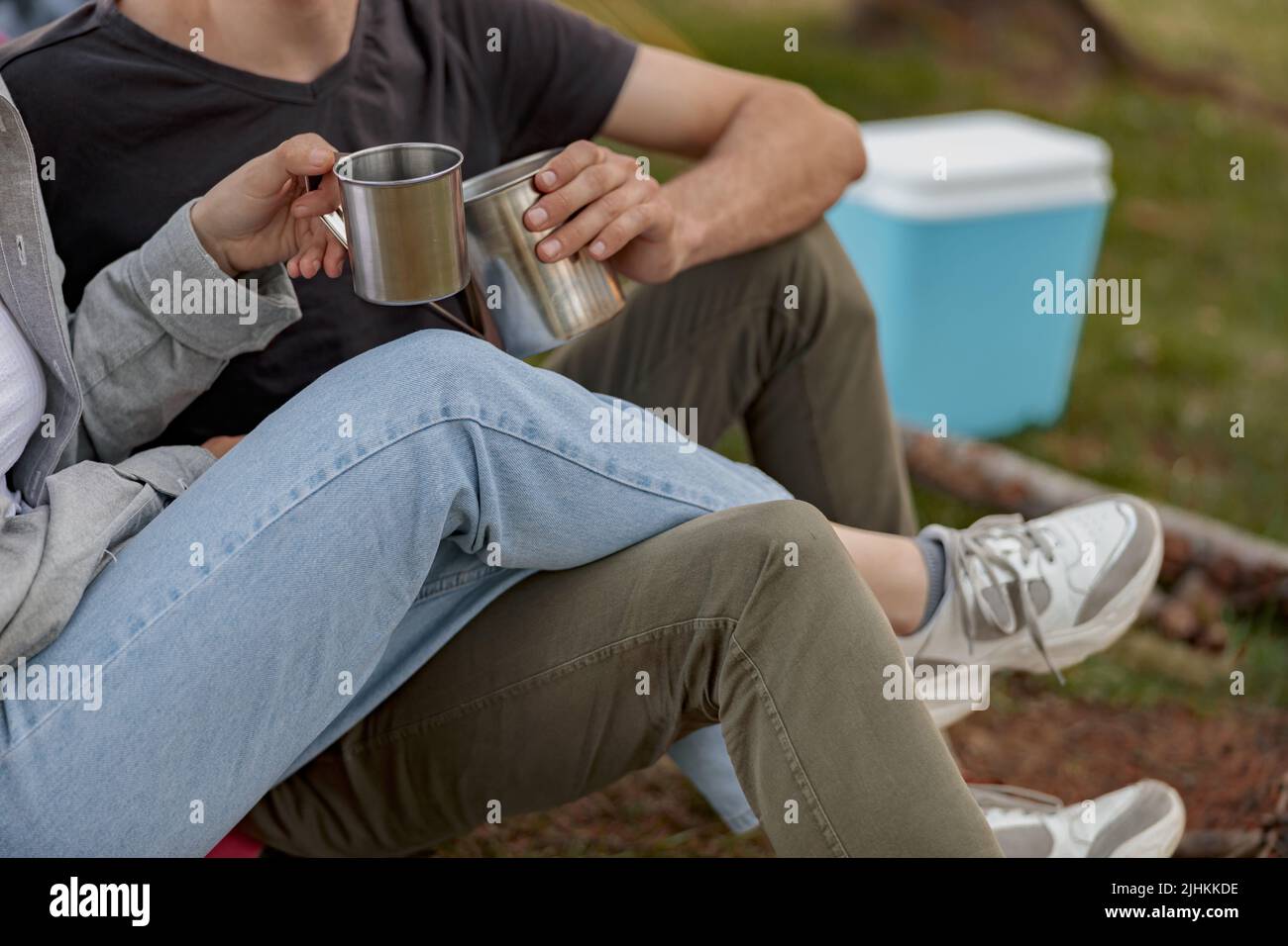 Close up of steel cups with coffee or tea in hands of couple. Picnic concept. Happy together. Stock Photo