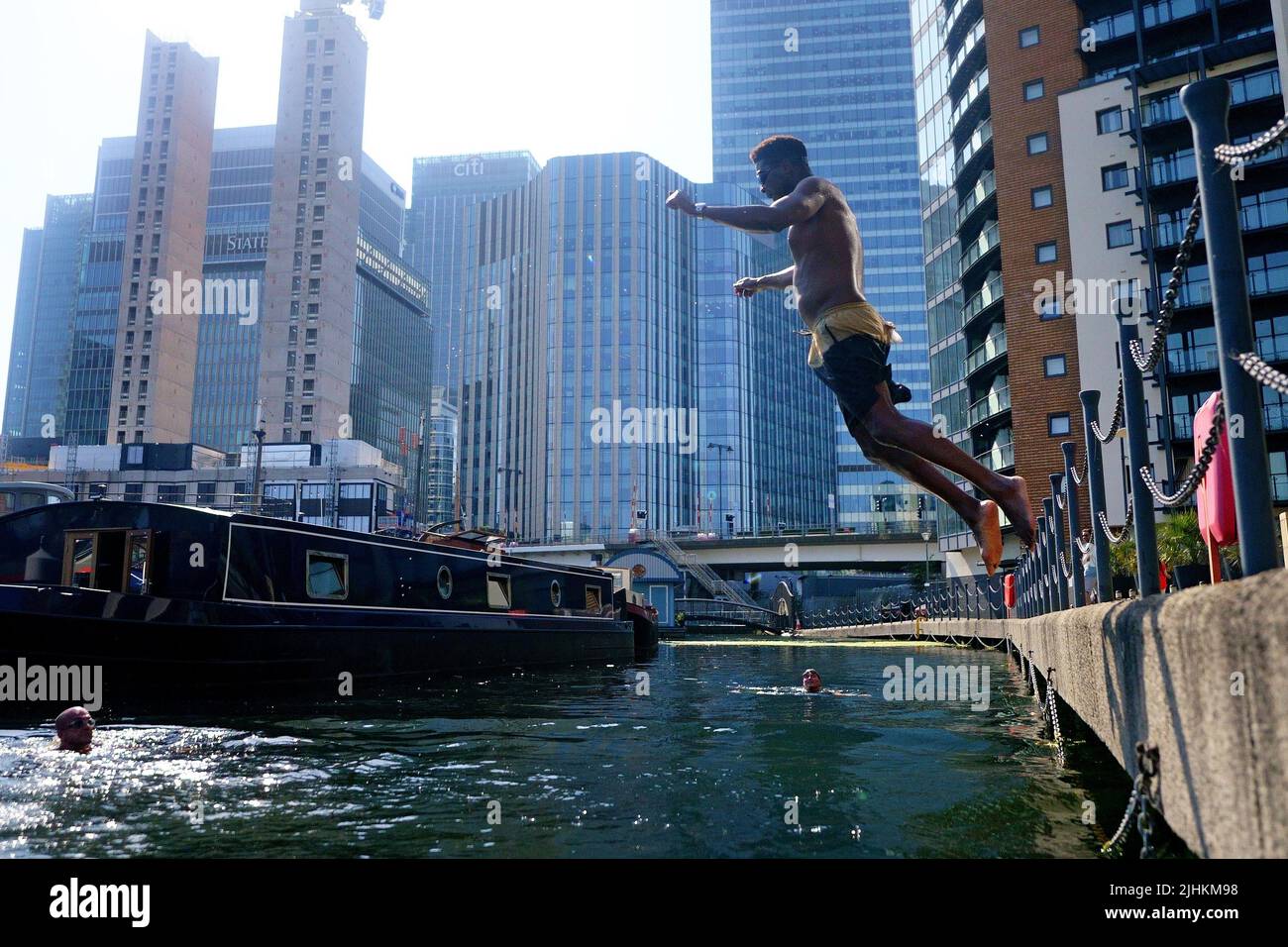 A swimmer dives into water in the Canary Wharf docklands in east London. Temperatures have reached 40C for the first time on record in the UK, with 40.2C provisionally recorded at London Heathrow, the Met Office has said. Picture date: Tuesday July 19, 2022. Stock Photo