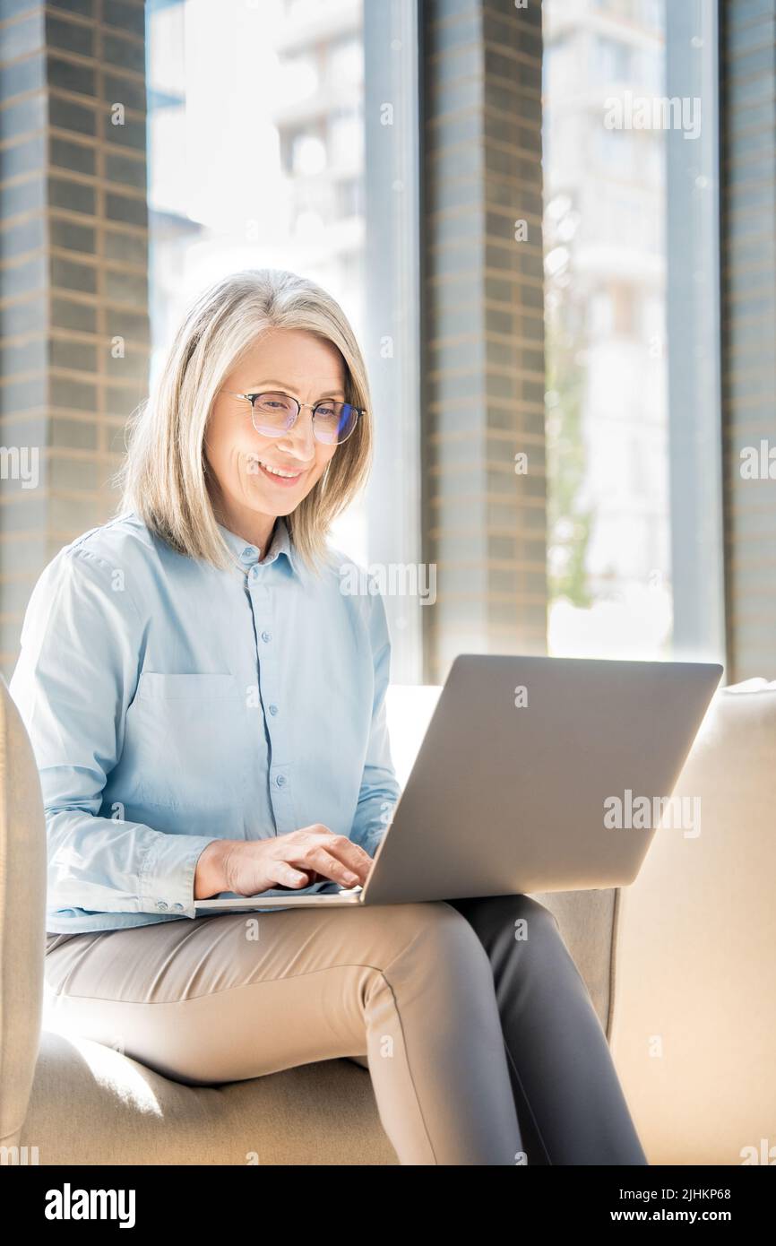 Senior woman works as a freelancer on laptop in a coworking. Stock Photo