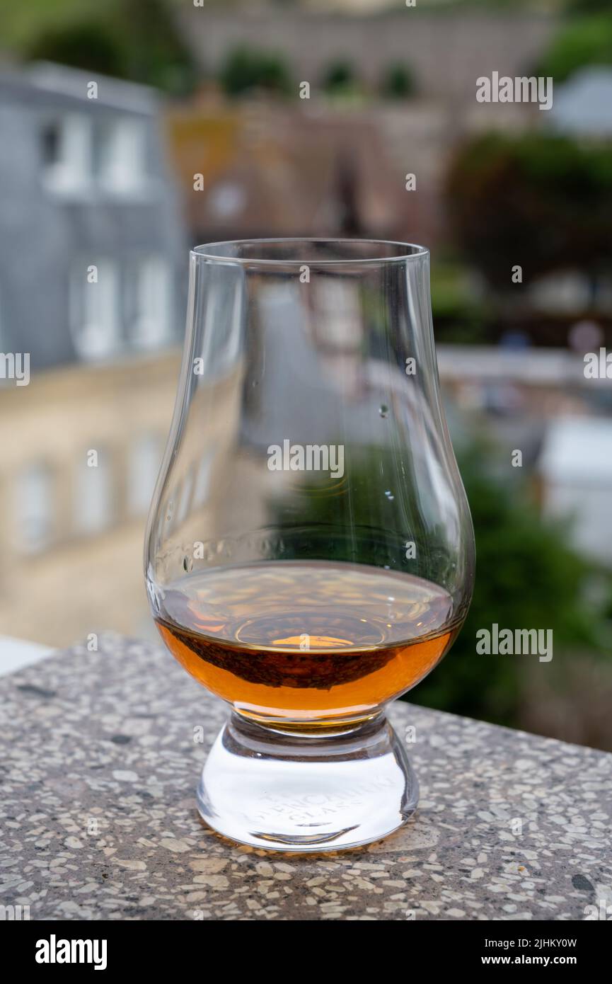 Dram of scotch whiskey with view on old houses on background, Edinburgh