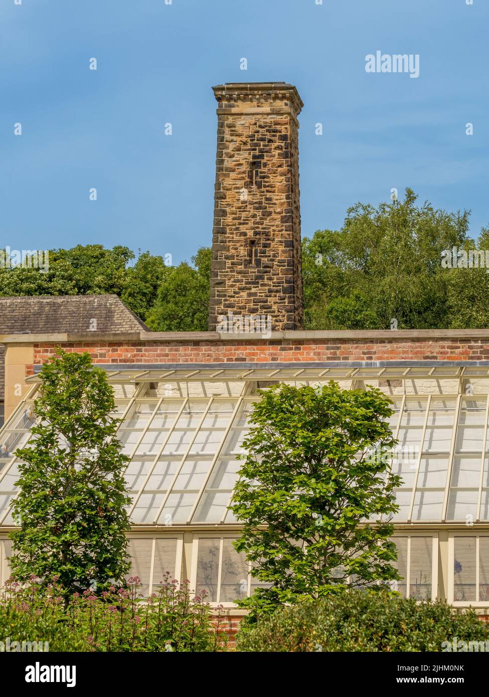 Large greenhouse in the walled garden with boiler house chimney behind at RHS Bridgewater. UK Stock Photo