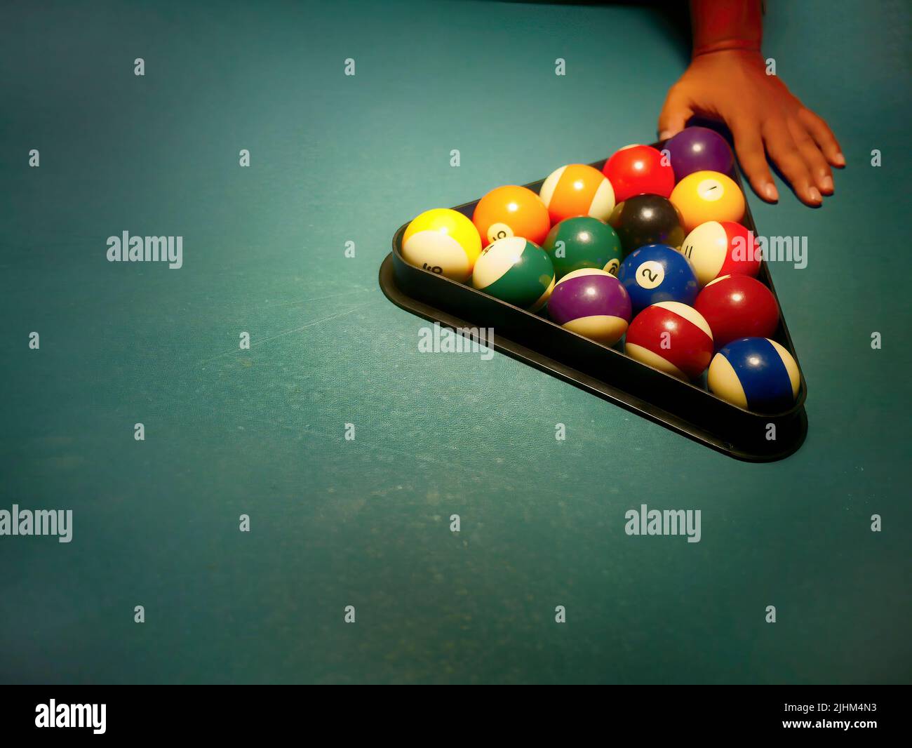 Hand preparing pool balls in triangle rack on the billiard table with