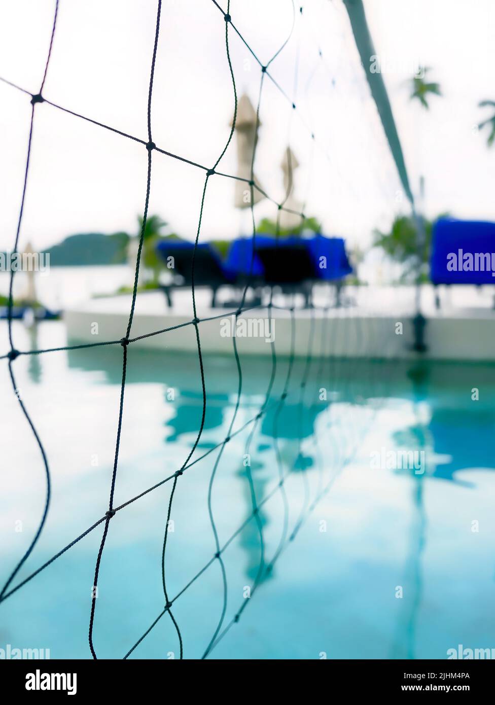 Detail of volleyball net over blue water swimming poo, Selective focus Stock Photo
