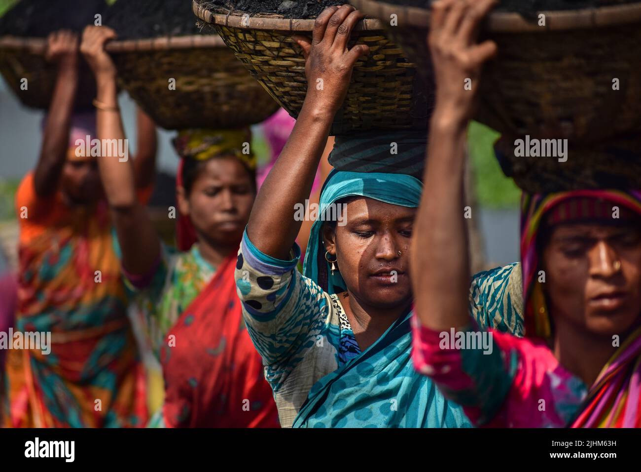 Women workers carrying baskets filled with coal on their head in the