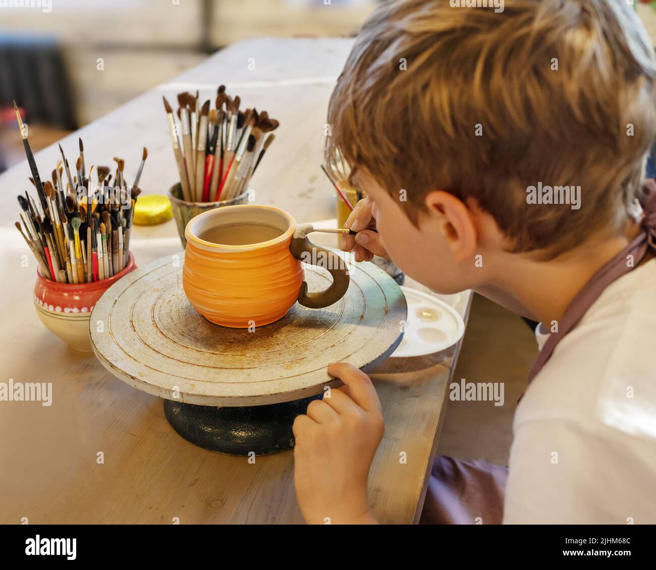 Boy coloring ceramic cup on a Potter's wheel at Hobbies