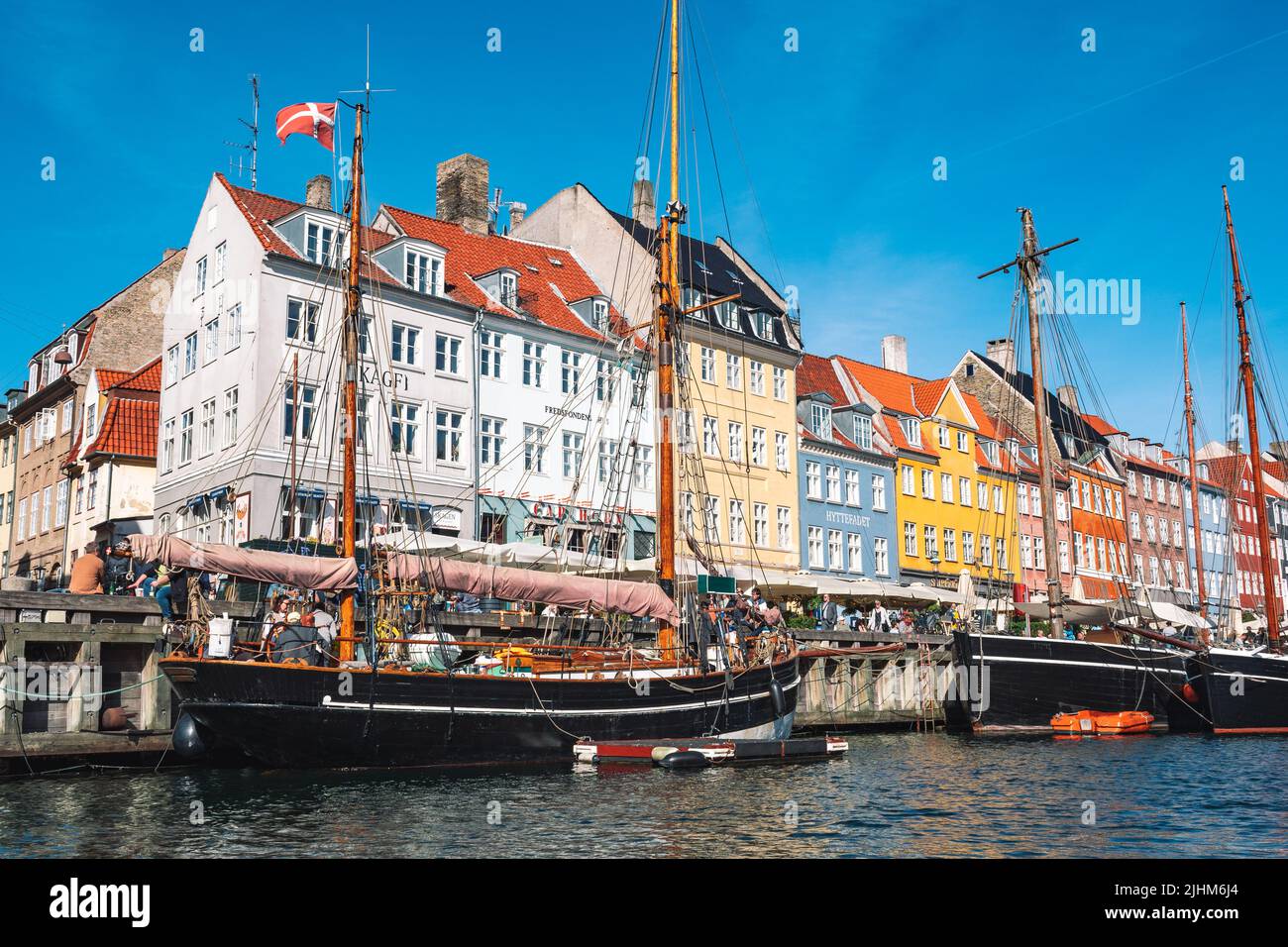 Beautiful view with colorful facade of traditional houses and old wooden ships, cruise boats along the Nyhavn Canal or New Harbour Stock Photo
