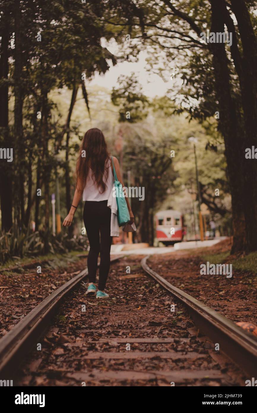 beautiful young woman walking backwads in the railroad Stock Photo