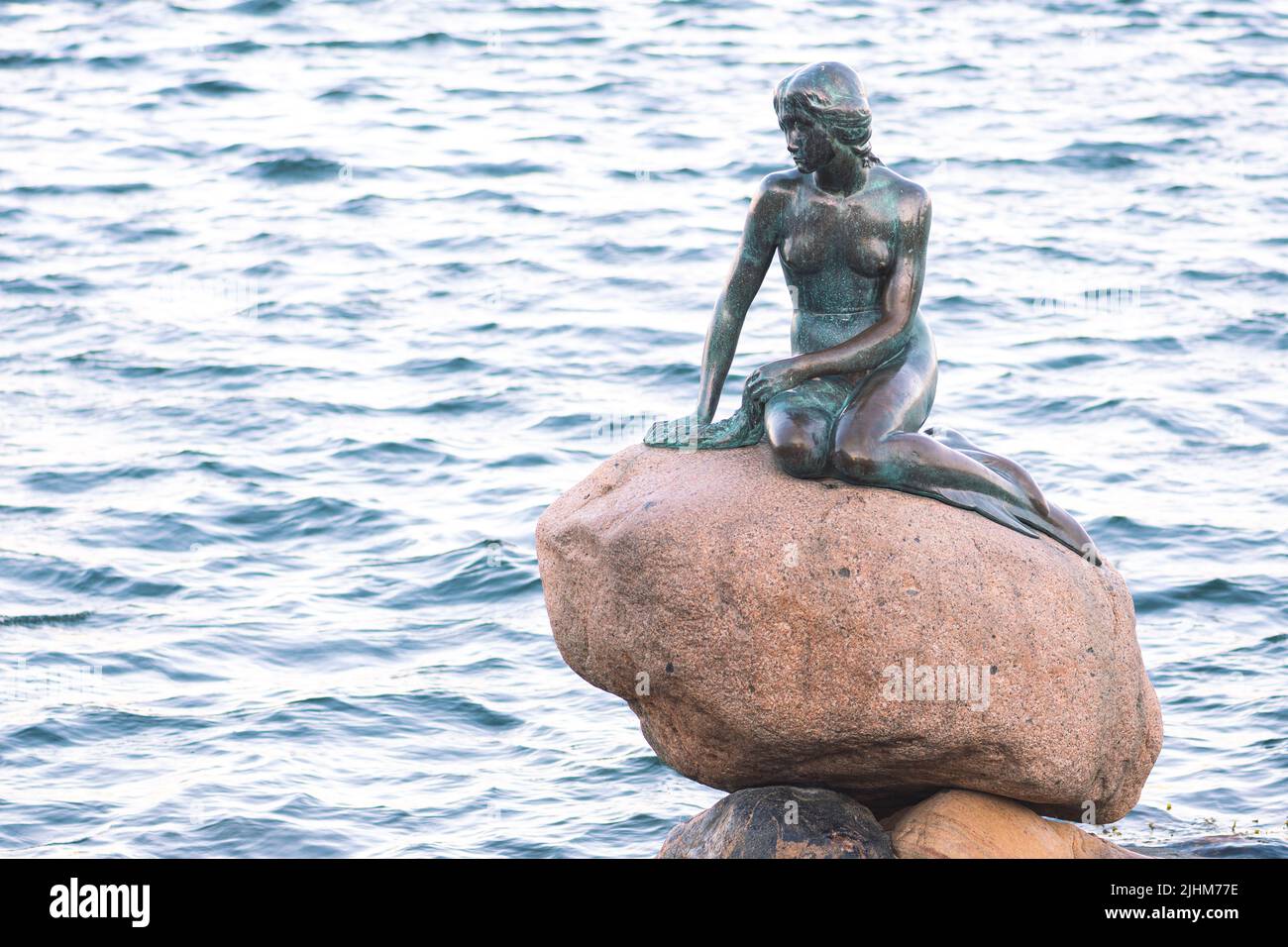 Bronze statue or sculpture of The Little Mermaid displayed on a rock by the waterside at the Langelinie promenade in Copenhagen, Denmark Stock Photo