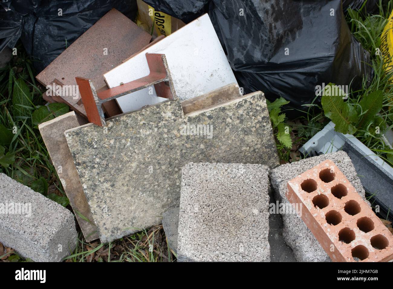 pile of new dumped bricks and blocks and bin bag with garbage Stock