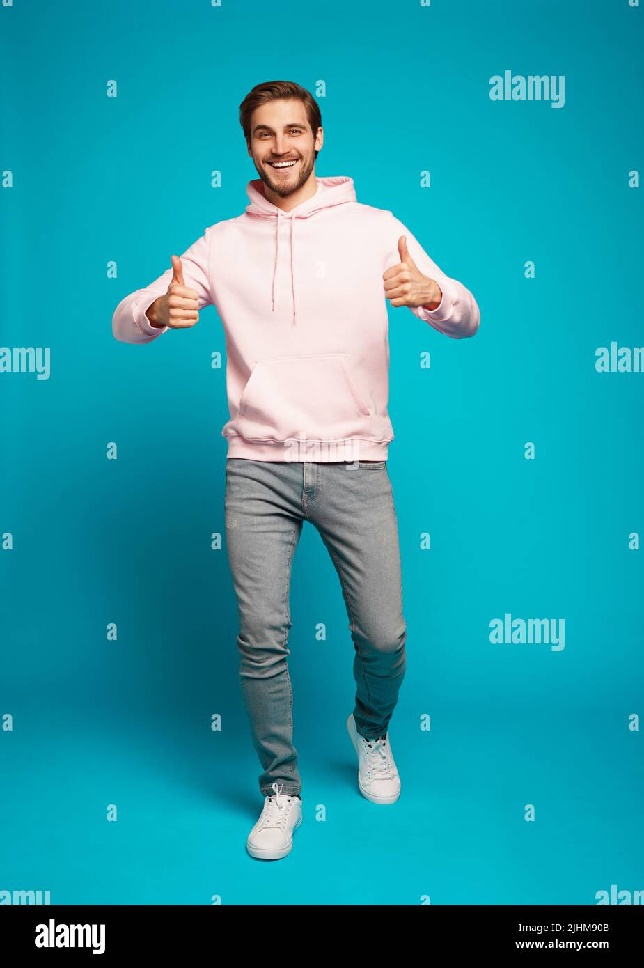 Full size photo of cheerful man smiling and showing thumbs up at camera isolated over light blue background Stock Photo