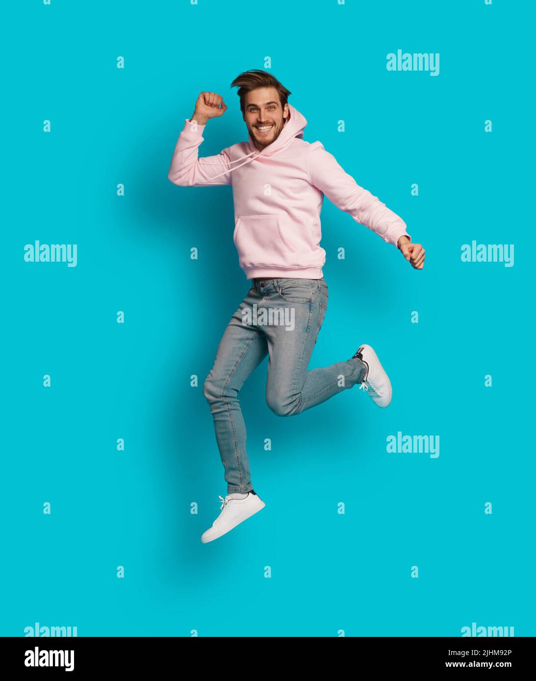 Full size photo of young happy excited smiling positive man jumping isolated on light blue color background Stock Photo