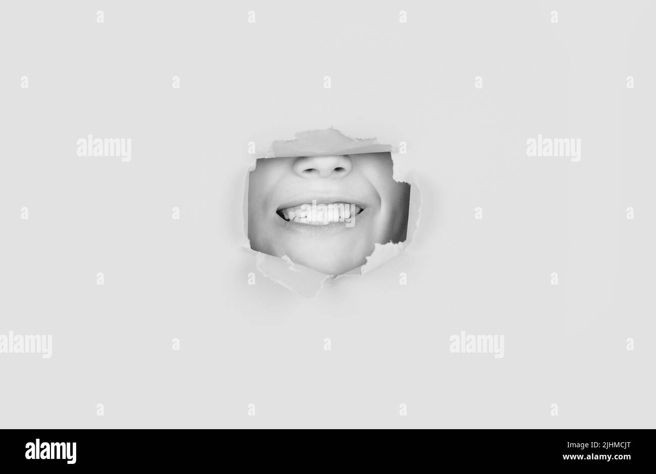 Breaking paper background. Emotions concept. Kid with toothy smile shows face in paper hole Stock Photo