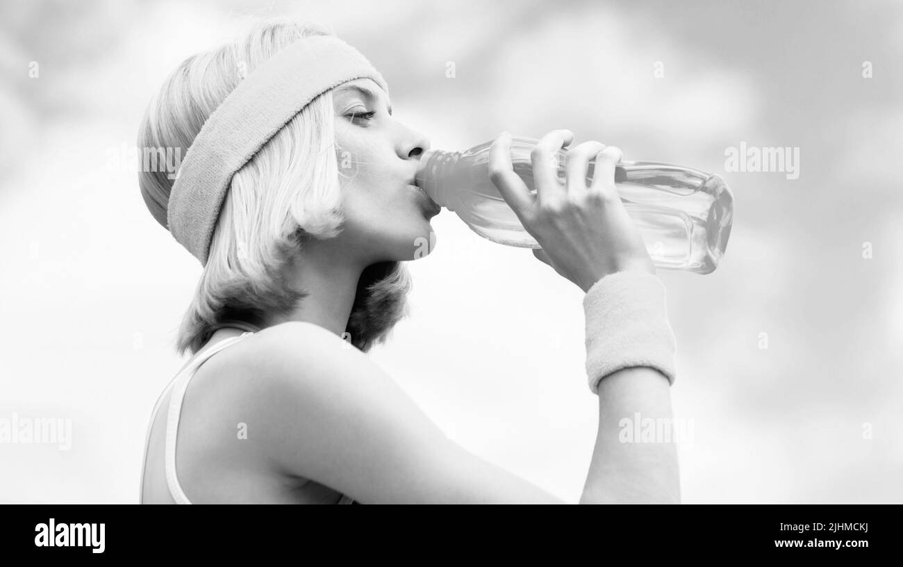 Drinking during sport. Young woman drinking water after run. Sports girl drinks water from a bottle on a sky background. Healthy lifestyle concept Stock Photo