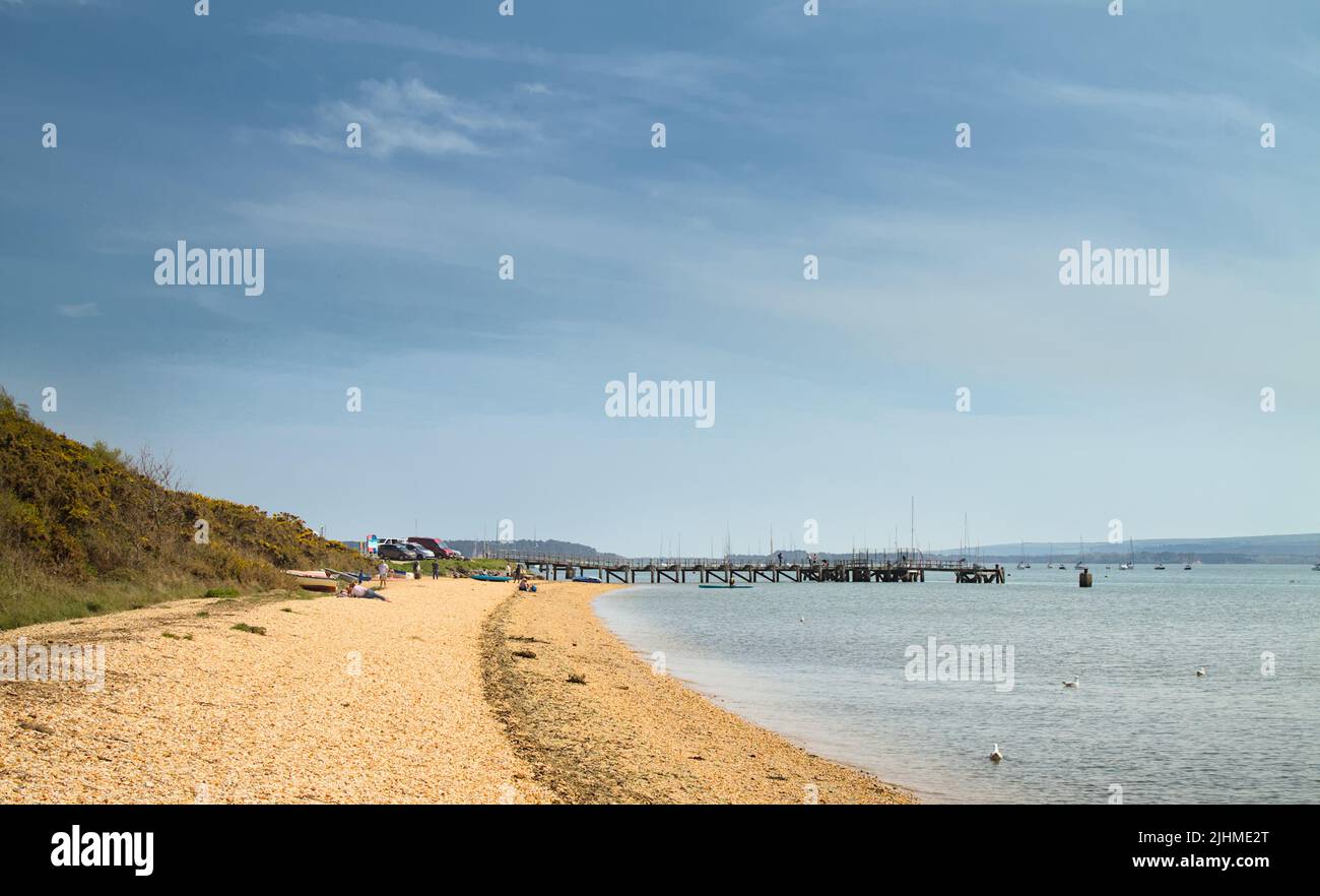 View Along The Northern Shore Of Poole Harbour Towards The Wooden Pier On Lake Pier Beach, Poole UK Stock Photo