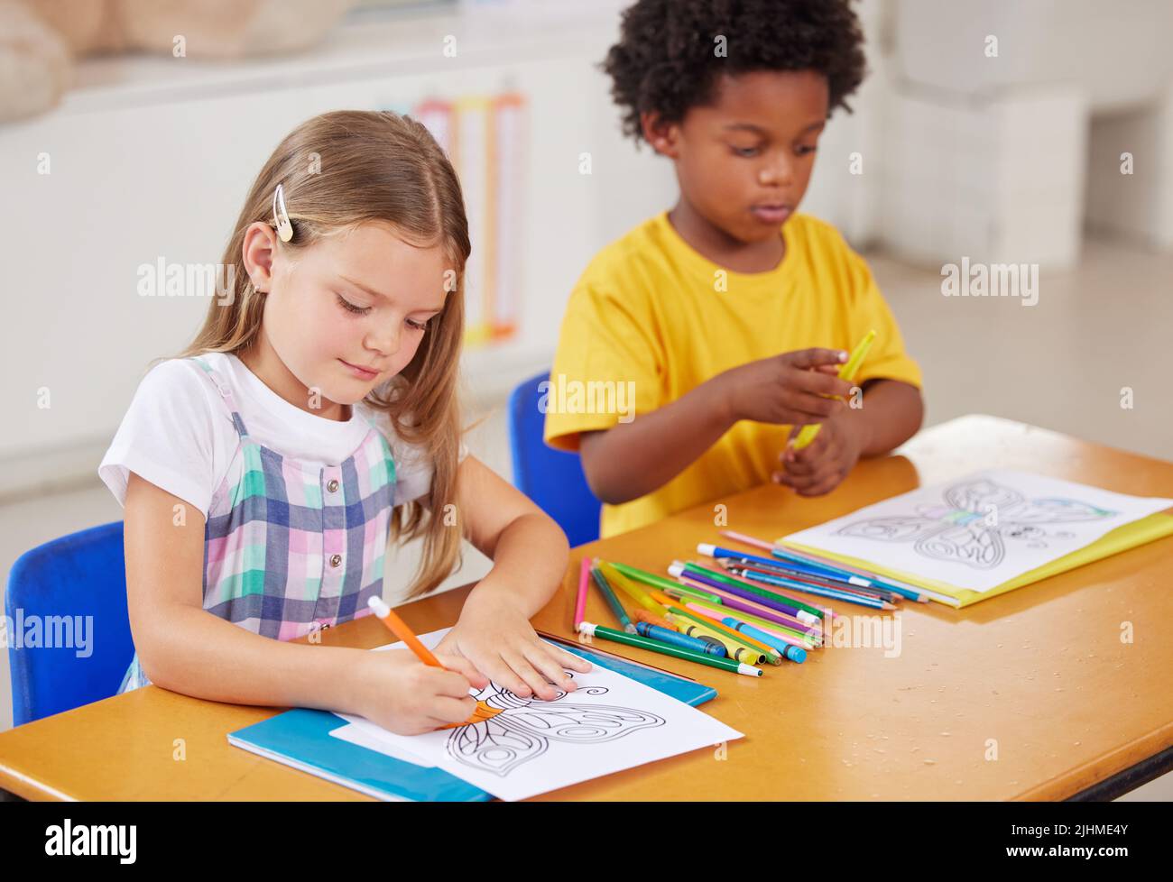 Colouring is a great sitting still activity. preschool students colouring in class. Stock Photo