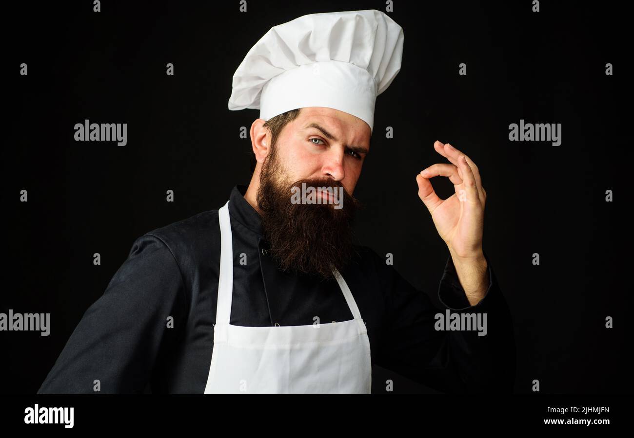 Professional chef in uniform shows sign for delicious. Cook or baker with taste approval gesture. Stock Photo