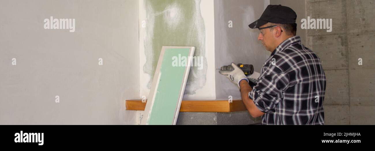 Image of a handyman who fixes plasterboard panels with a screwdriver. Do-it-yourself work. Horizontal banner Stock Photo