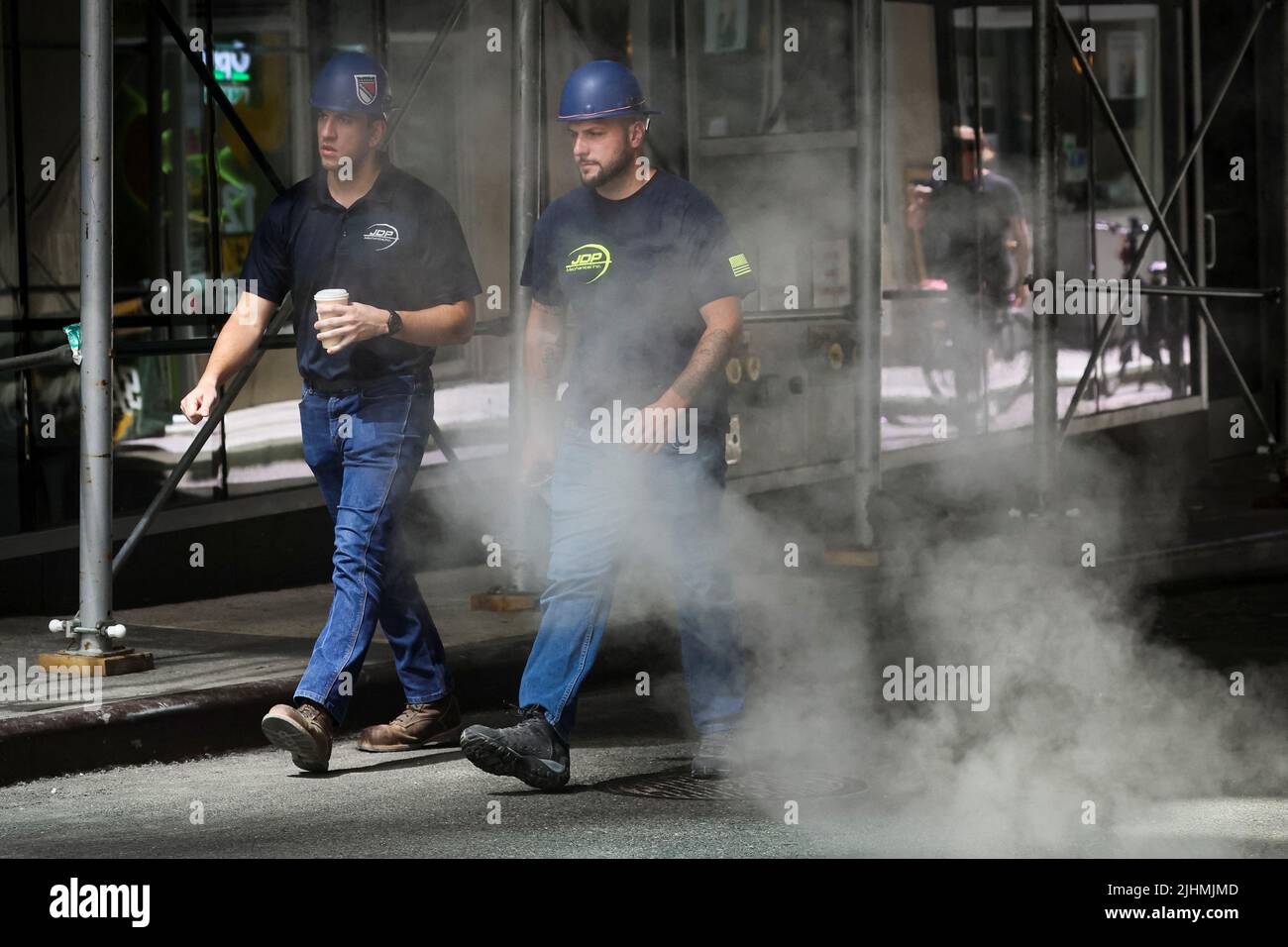 Workers walk through a cloud of steam during a heatwave in New York City, U.S., July 19, 2022.  REUTERS/Brendan McDermid Stock Photo