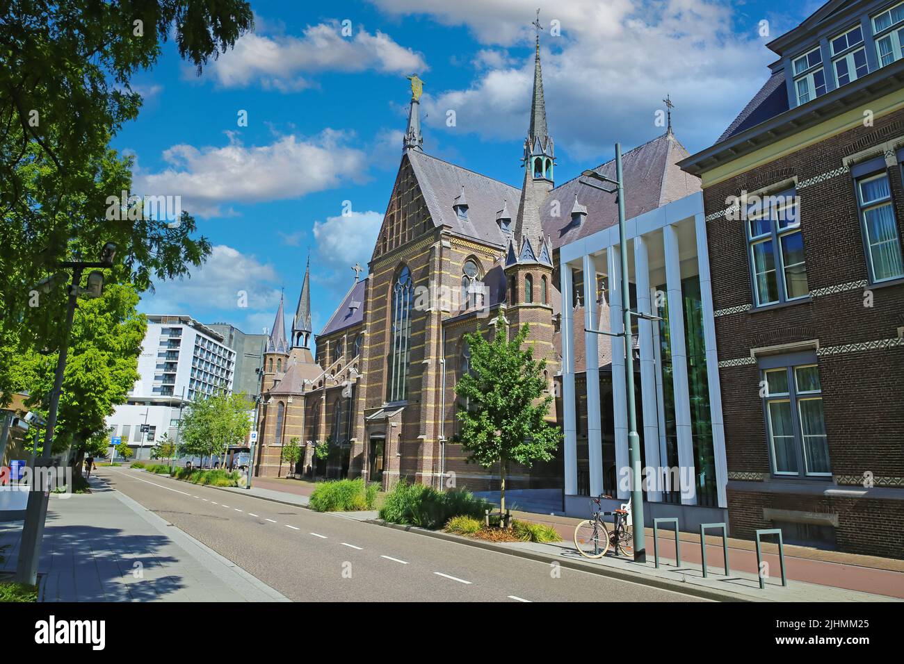 Eindhoven, Netherlands - July 17. 2022: City street with medieval gothic augustine church and marienhage hotel, blue summer sky fluffy clouds Stock Photo