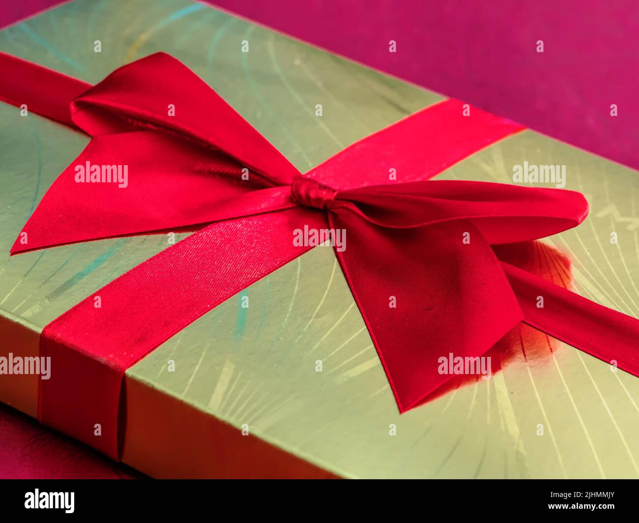 Closeup of golden chocolate box with red ribbon Stock Photo