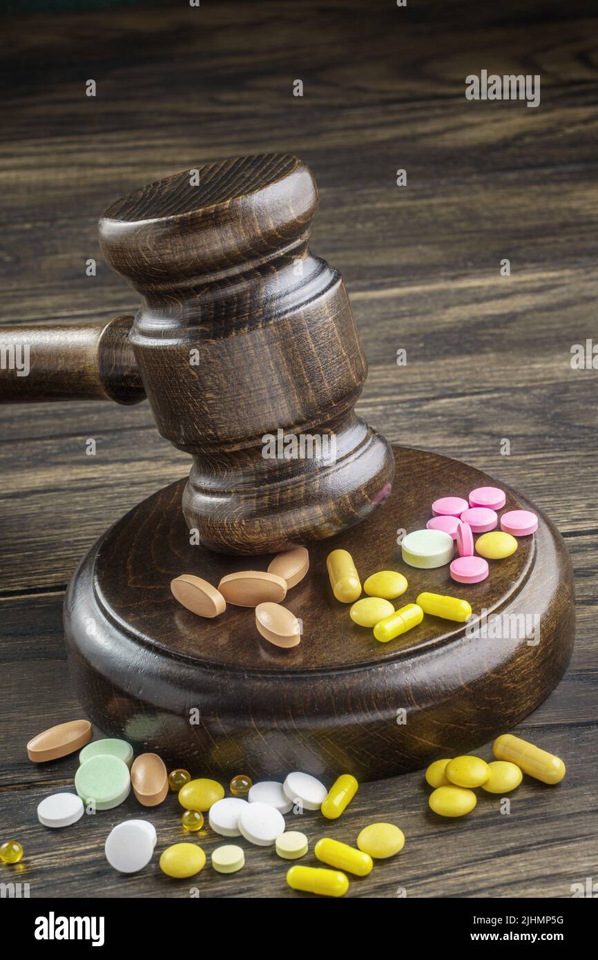 Wooden gavel with drugs on table, closeup. Forensic medicine, pharmaceutical problems in medical practice, expired drugs, fake market. Stock Photo