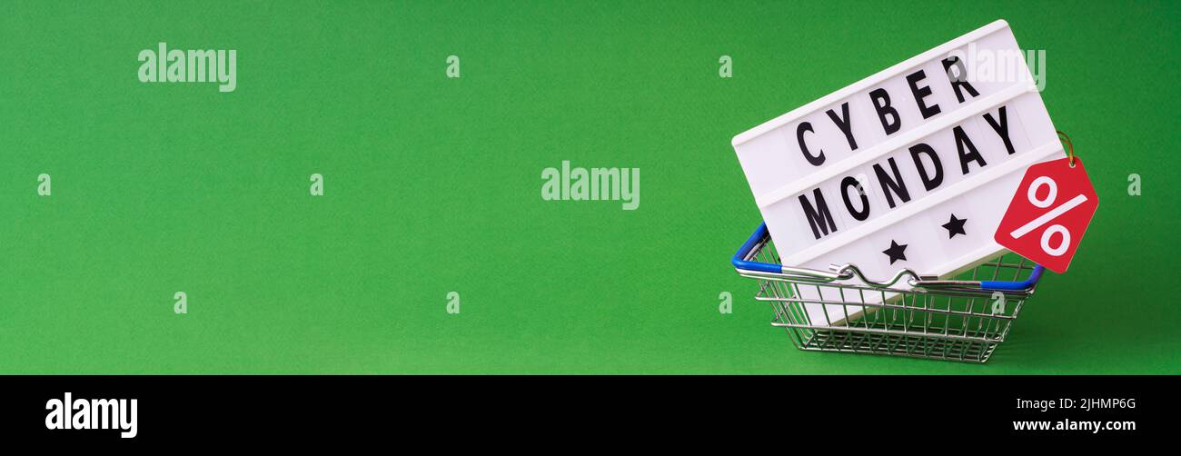 Cyber monday spelled in letters on light box in shopping basket, black friday concept on green background Stock Photo