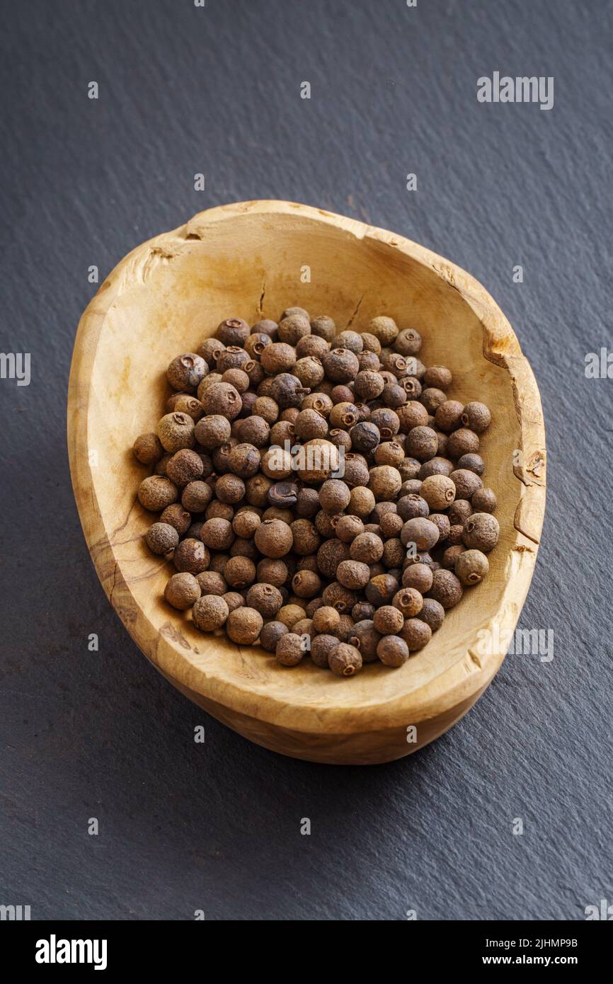 Allspice in wooden bowl on dark slate background with copy space Stock Photo