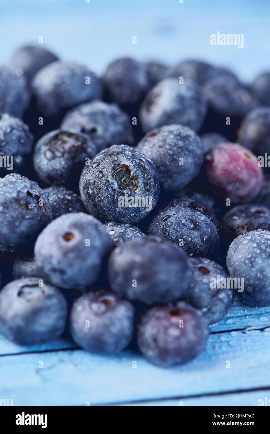 vertical photo with close up of blueberries against blue background Stock Photo