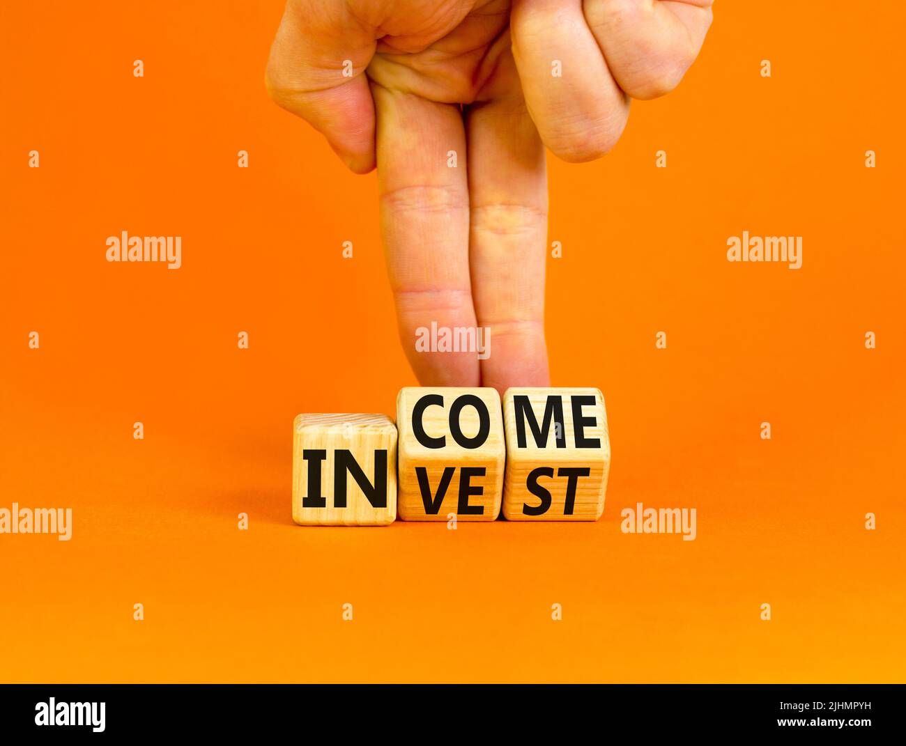 Invest or income symbol. Concept words Invest and Income on wooden cubes. Businessman hand. Beautiful orange table orange background. Business and inv Stock Photo