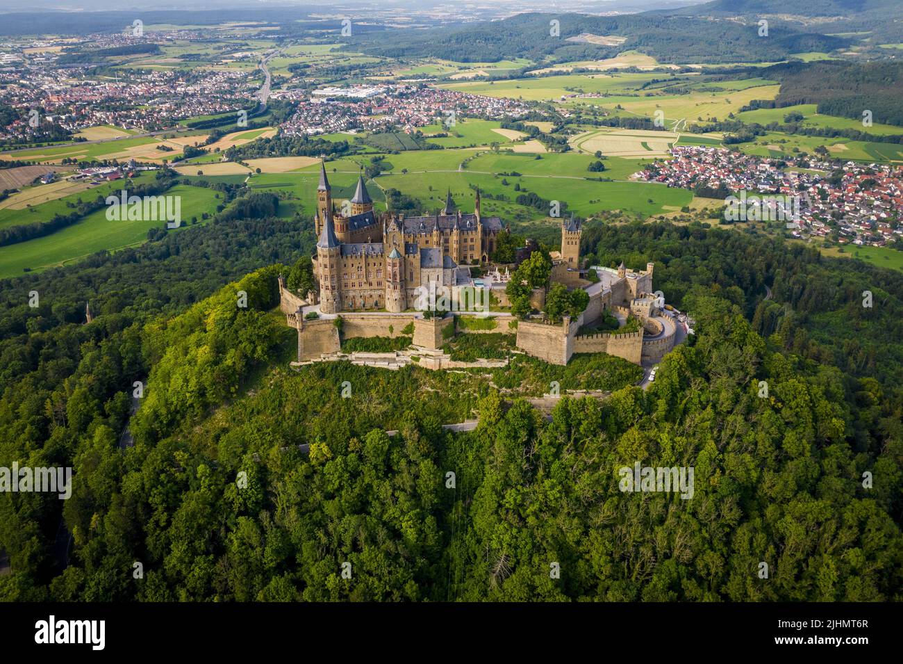Drone Shot Of Hohenzollern Castle On Forested Mountain Top In The drone-shot-of-hohenzollern-castle-on-forested-mountain-top-in-the