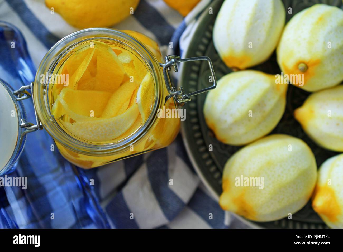 glass jar with lemon zest inside, next to fresh peeled lemons