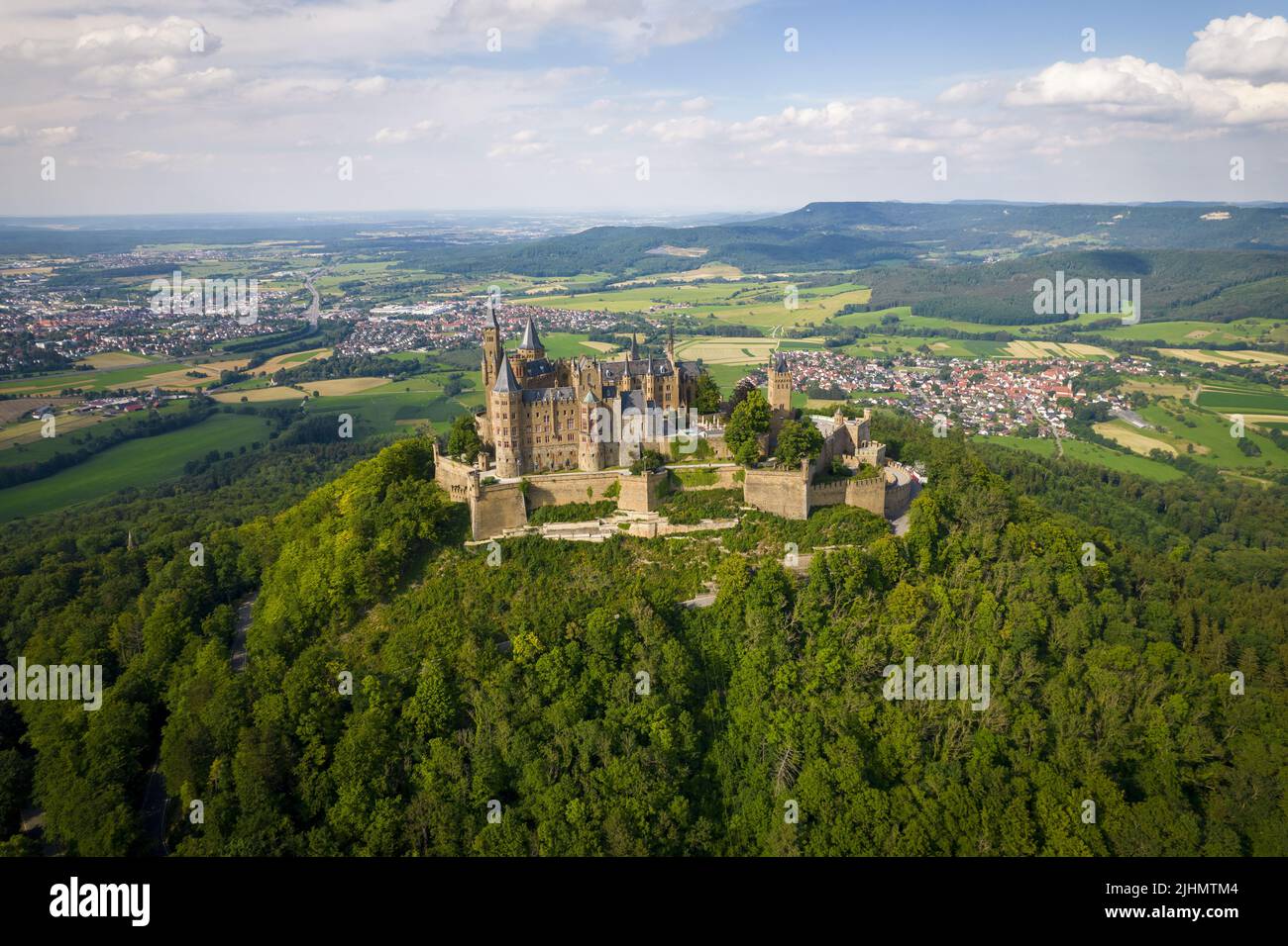 Drone shot of Hohenzollern Castle on forested mountain top in the ...