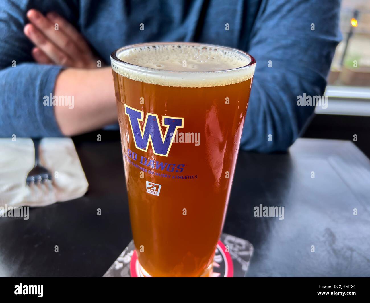 Seattle, WA USA - circa June 2022: Close up view of a frothy beer in a University of Washington glass inside a local bar. Stock Photo
