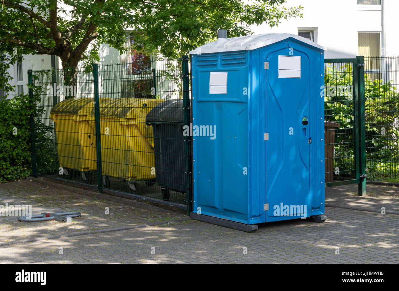 yellow recycling bins and blue mobile toilet Stock Photo Alamy
