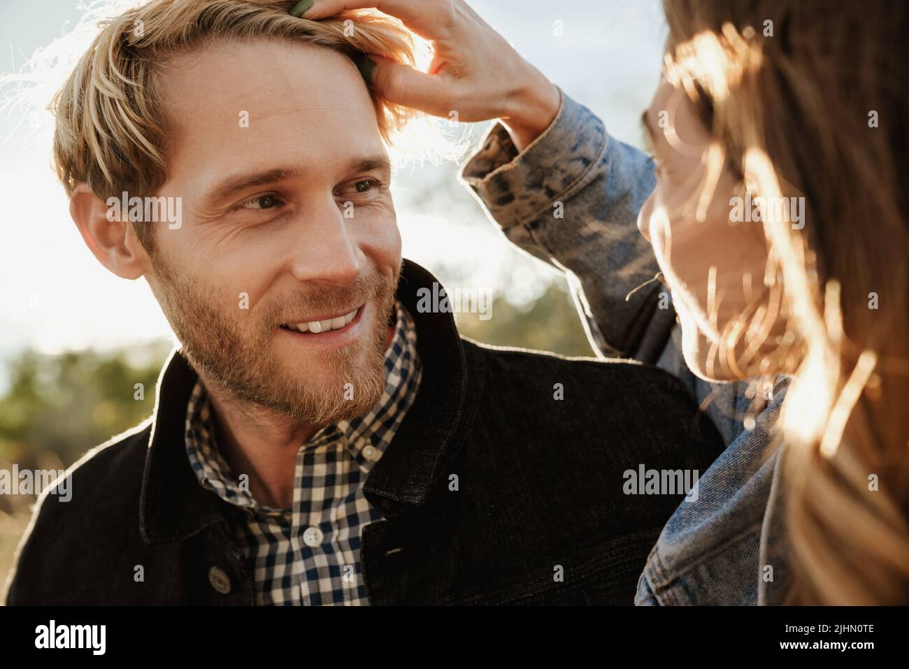 White mid couple smiling and looking at each other while standing outdoors Stock Photo