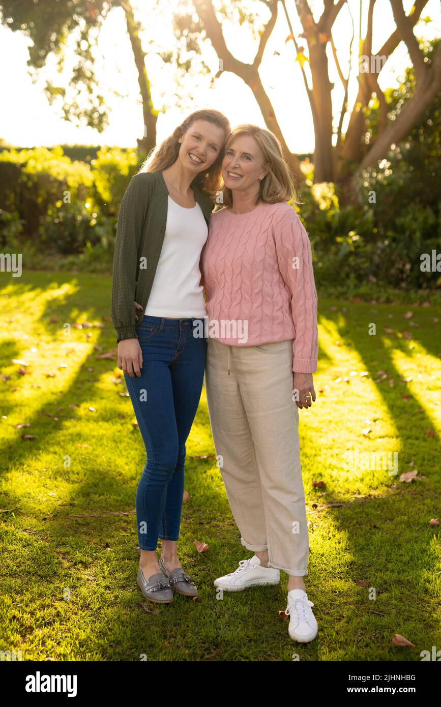 Vertical image of happy caucasian mother and adult daughter posing at