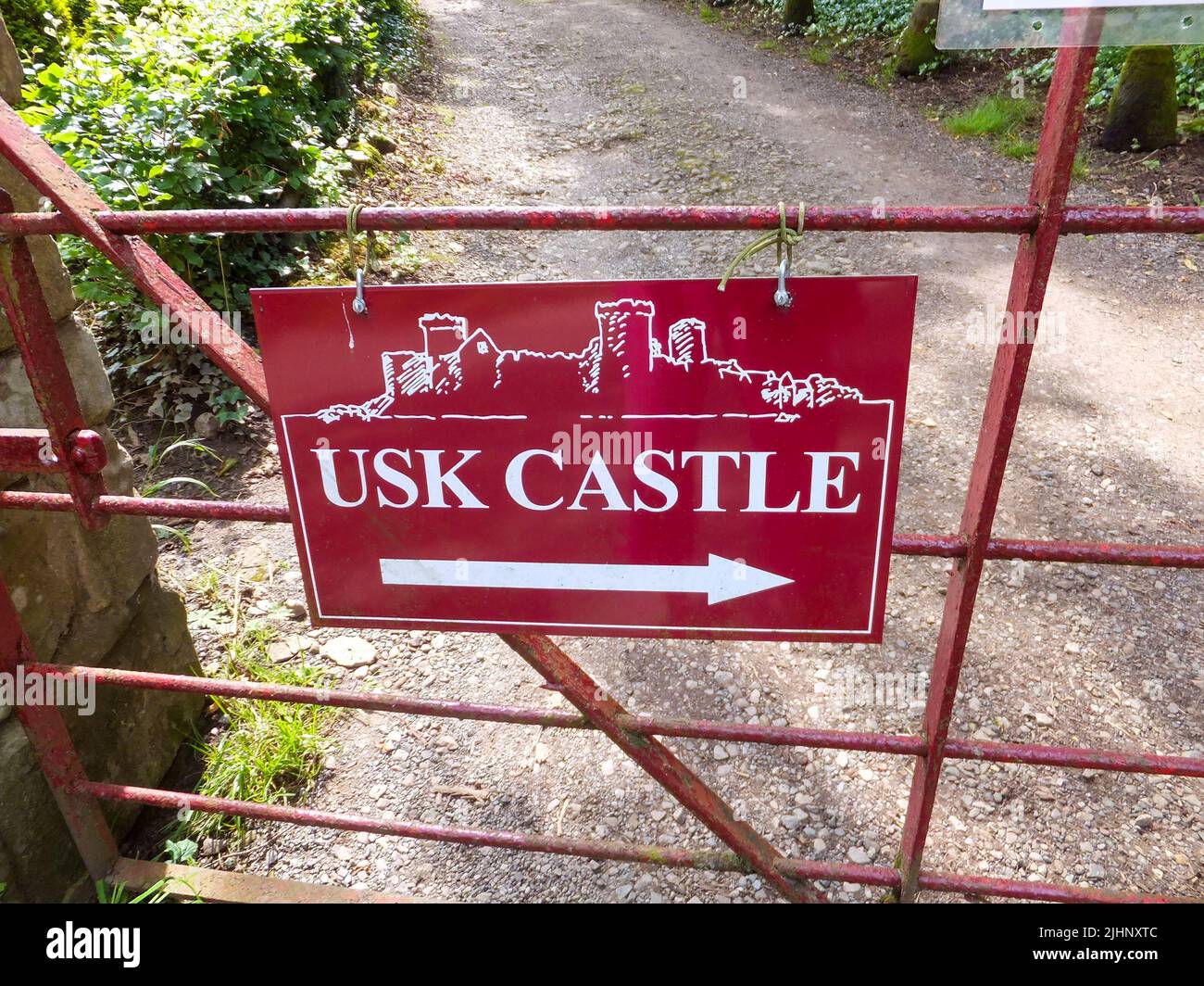 A red sign on a closed gate pointing to Usk Castle in Usk, Monmouthshire, Wales, UK. Stock Photo