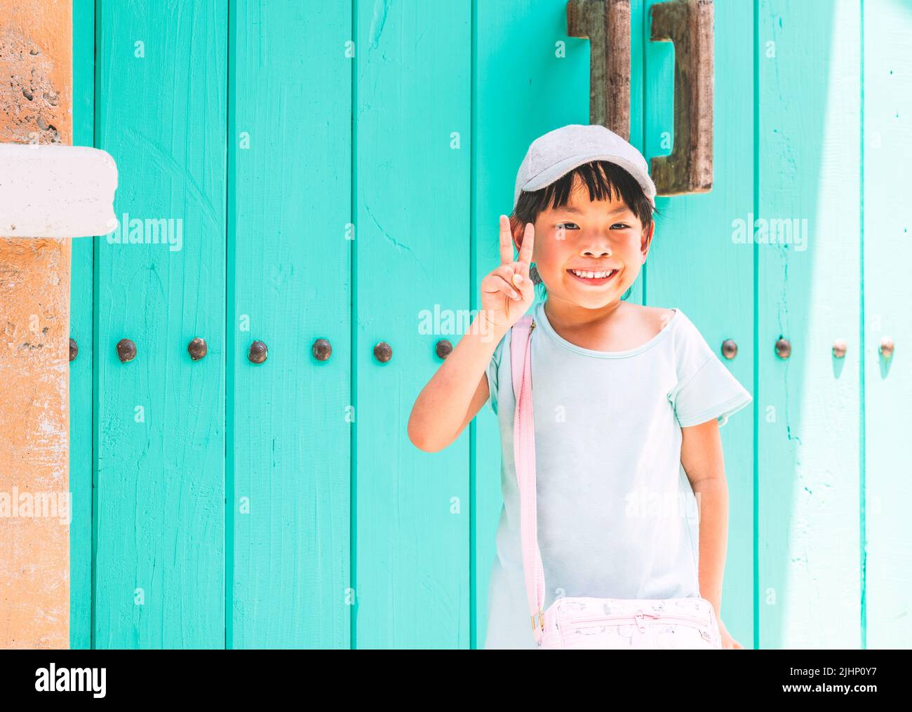 Portrait Asian cute small child girl at 5 years old on vacation, smiling face, posing with two fingers to show the happy time, background of vintage c Stock Photo