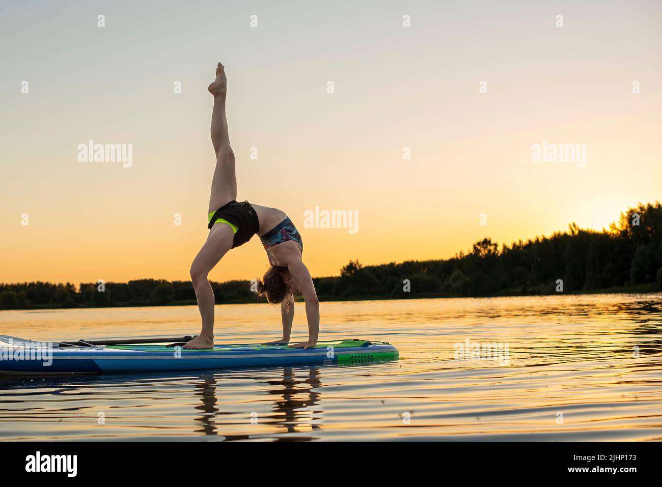 Sport woman yogini scorpion pose practice yoga exercise on sup board on the sea in relaxing day , yoga is meditation and healthy sport concept.yoga on Stock Photo
