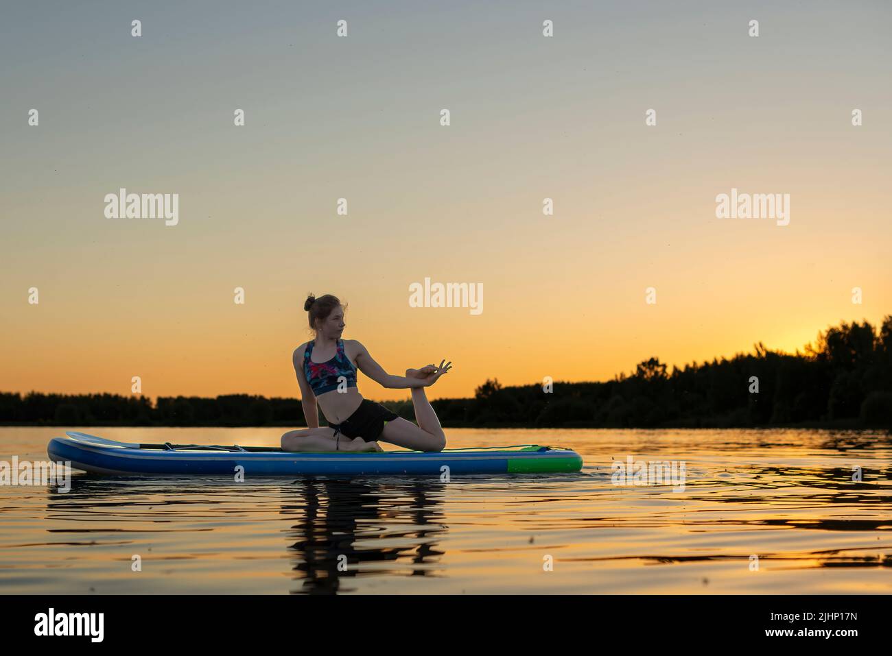 Sport woman yogini scorpion pose practice yoga exercise on sup board on the sea in relaxing day , yoga is meditation and healthy sport concept.yoga on Stock Photo