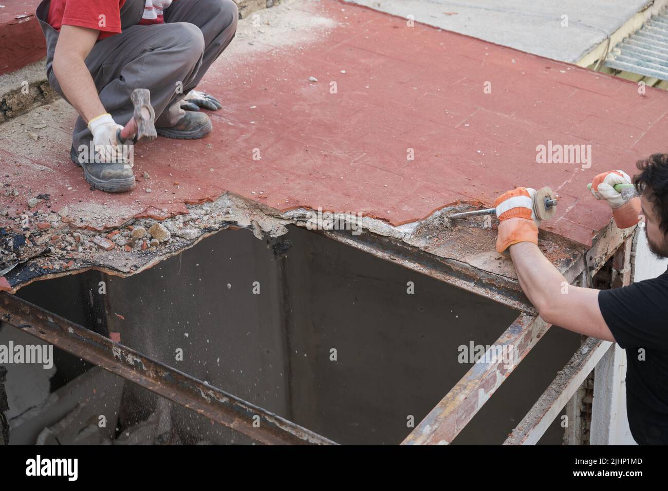 Two builders pulling the roof of a house down. Stock Photo