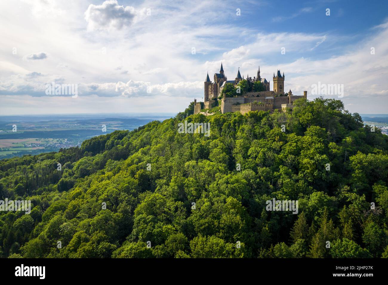 Drone shot of Hohenzollern Castle on forested mountain top in the ...